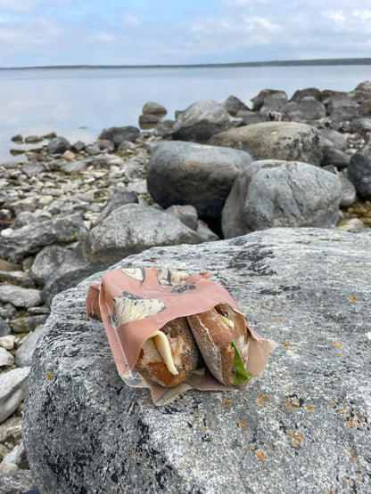 Deli bivaxpåse med smörgåsar i som ligger på en klippa 